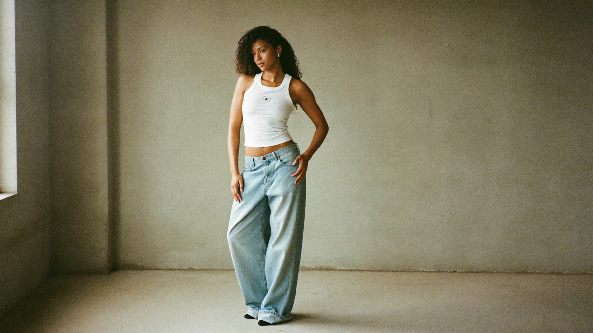 Woman wearing baggy light wash WILDER DENIM jeans in a concrete studio